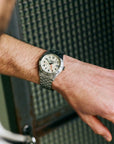 Close-up of a wrist wearing a silver watch with a textured background