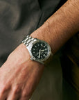 Close-up of a wrist wearing a silver watch with a black face.
