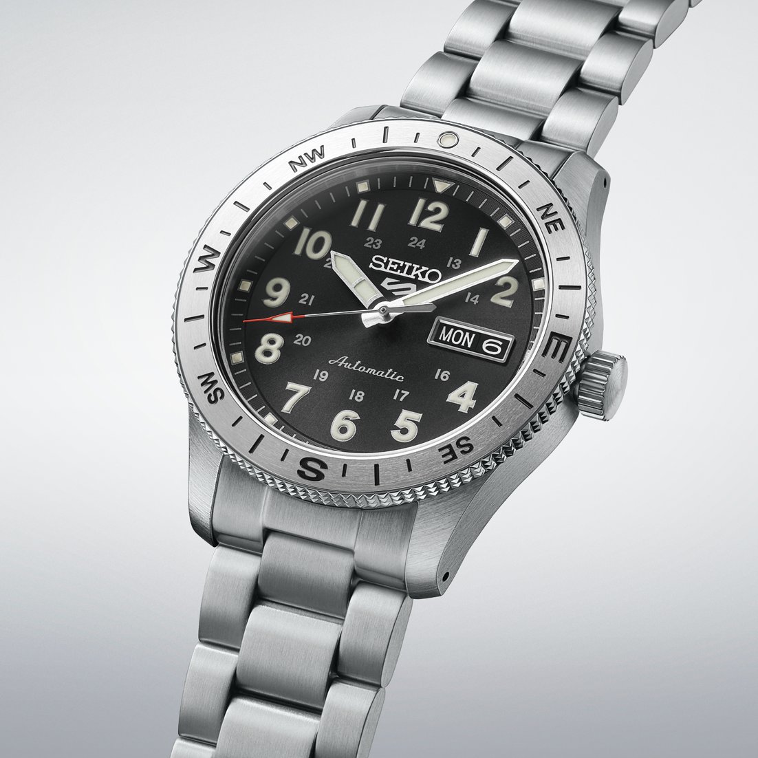 Silver Seiko watch with black dial on a light gray background- angled
