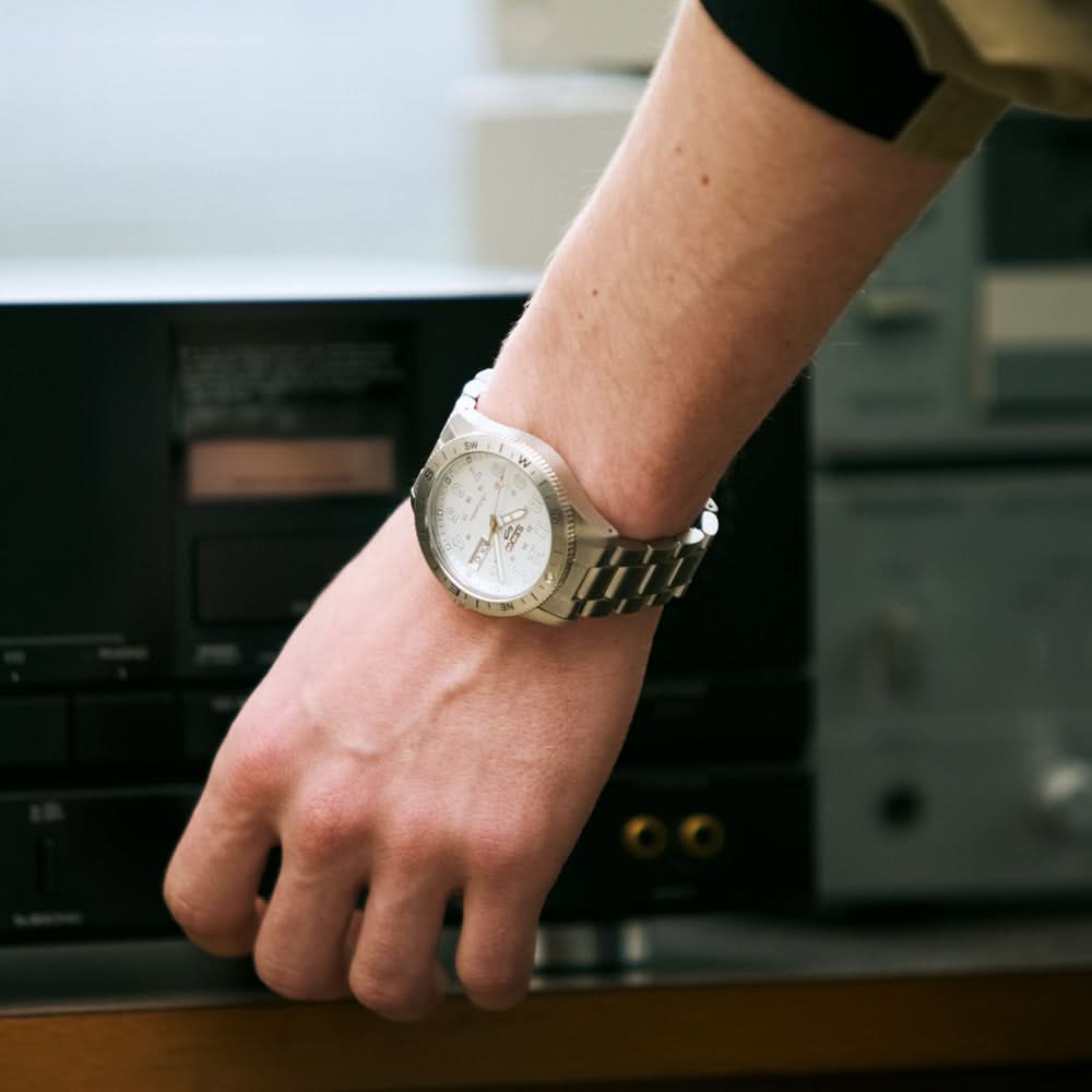 Hand wearing a gold watch with a blurred background