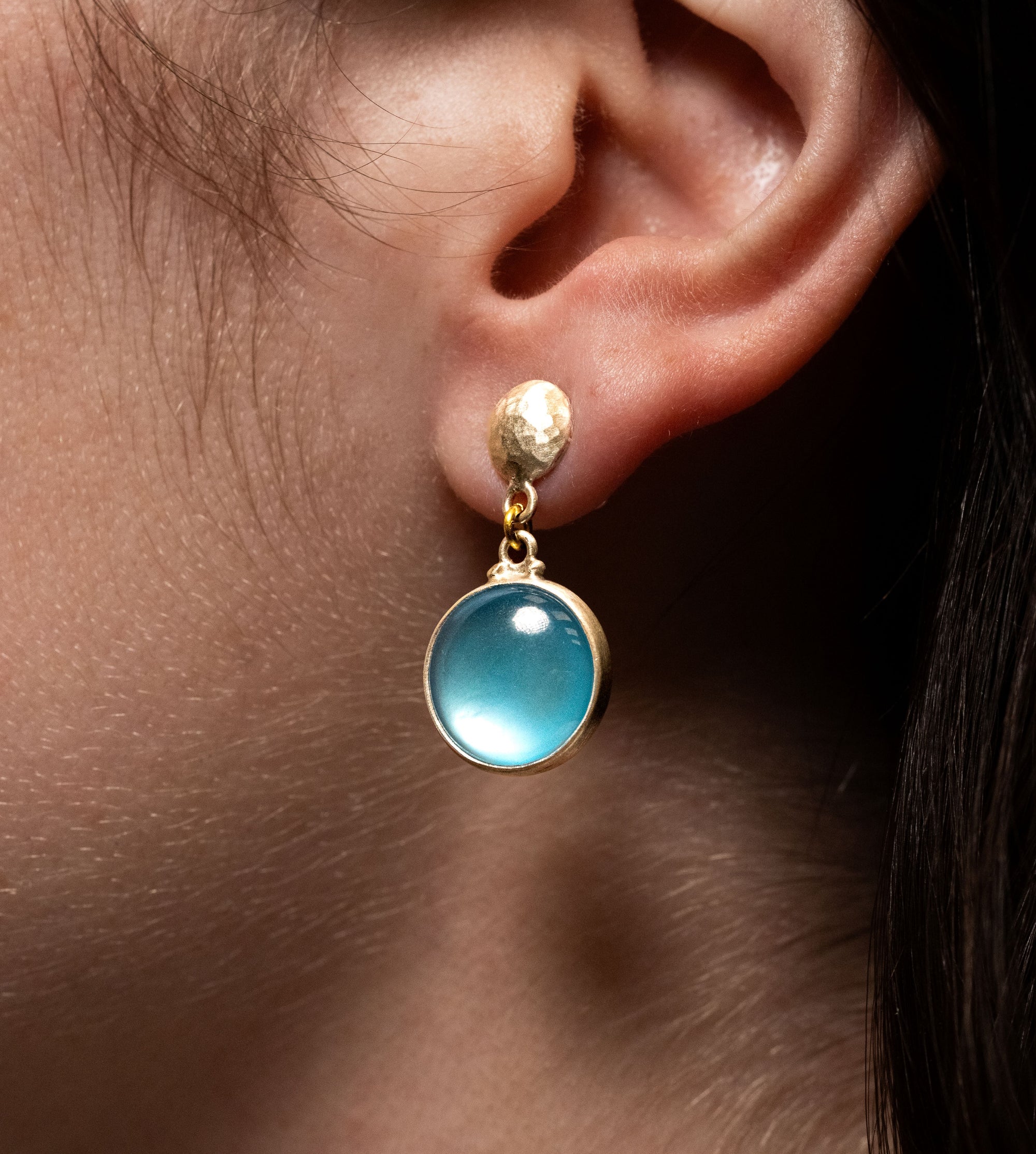 Blue topaz in sterling silver and button top earrings modeled on an ear.