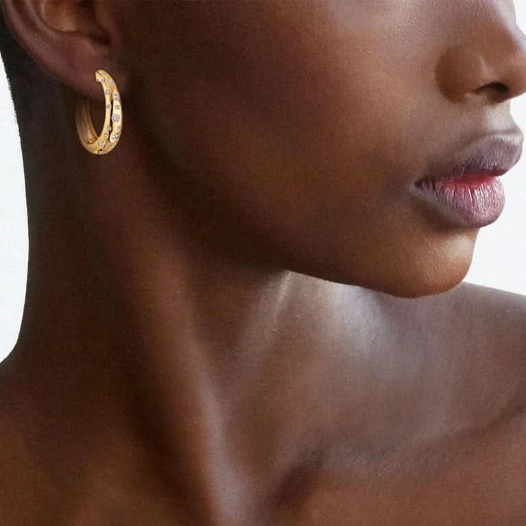 Person wearing yellow gold hoop with embedded diamonds