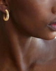 Person wearing yellow gold hoop with embedded diamonds