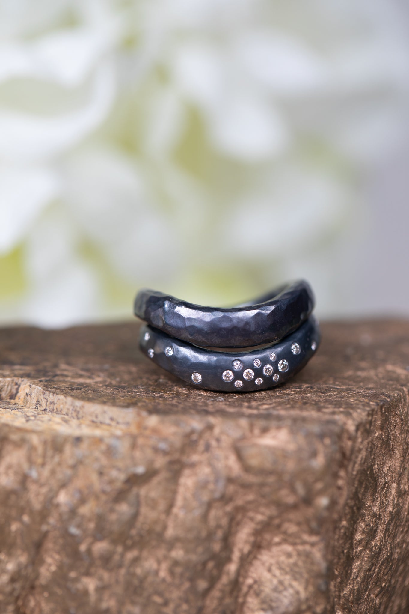 Two black rings with silver accents on a wooden surface with a blurred natural background