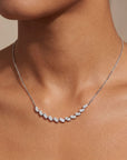 white gold  necklace with small diamonds on a person's neck against a neutral background