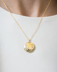 close up of a neck wearing a gold necklace with a round locket with multi shaped diamonds on a white background