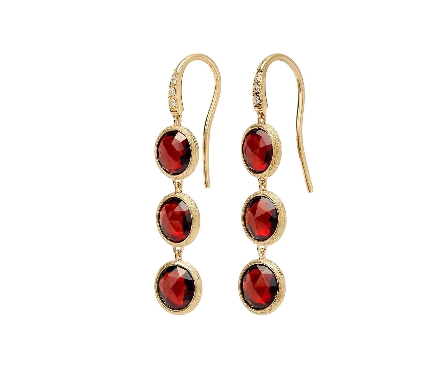 A pair of gold drop earrings featuring three faceted round red gemstones in a textured gold bezel setting, suspended from gold French hooks with a small clear accent stone near the top.