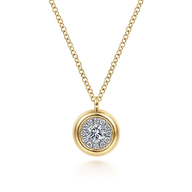 A gold pendant necklace featuring a round yellow gold outer ring and a central halo of small clear stones around a larger clear center stone, suspended from a delicate gold chain on a white background.