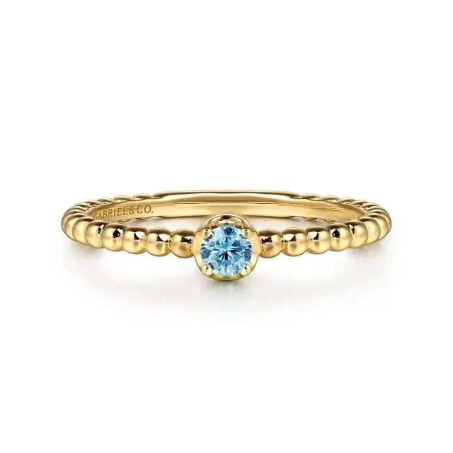 Gold ring with a blue gemstone on a white background
