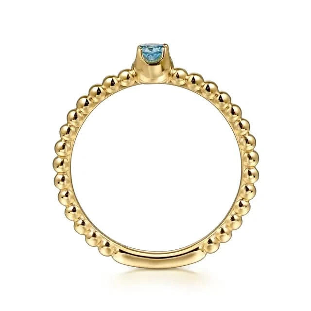 Gold ring with a blue gemstone on a white background top view