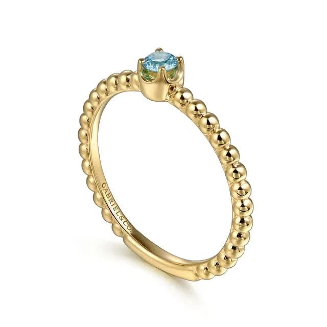Gold ring with a blue gemstone on a white background angled