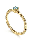 Gold ring with a blue gemstone on a white background angled