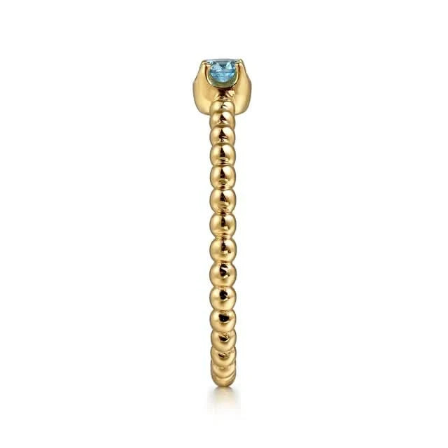 Gold ring with a blue gemstone on a white background side view