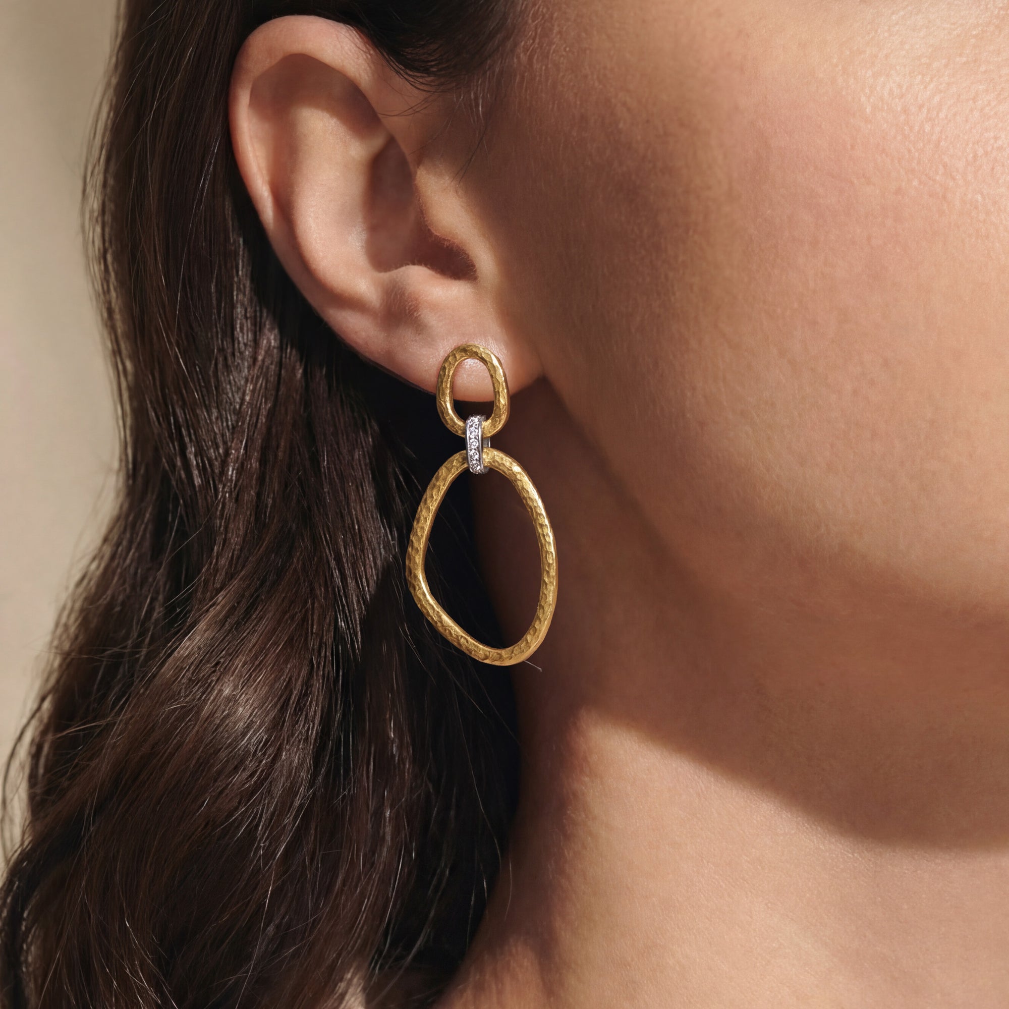 Gold earring worn by a person with brown hair.