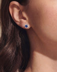 Close-up of an ear wearing a blue gemstone earring with diamonds with a blurred background