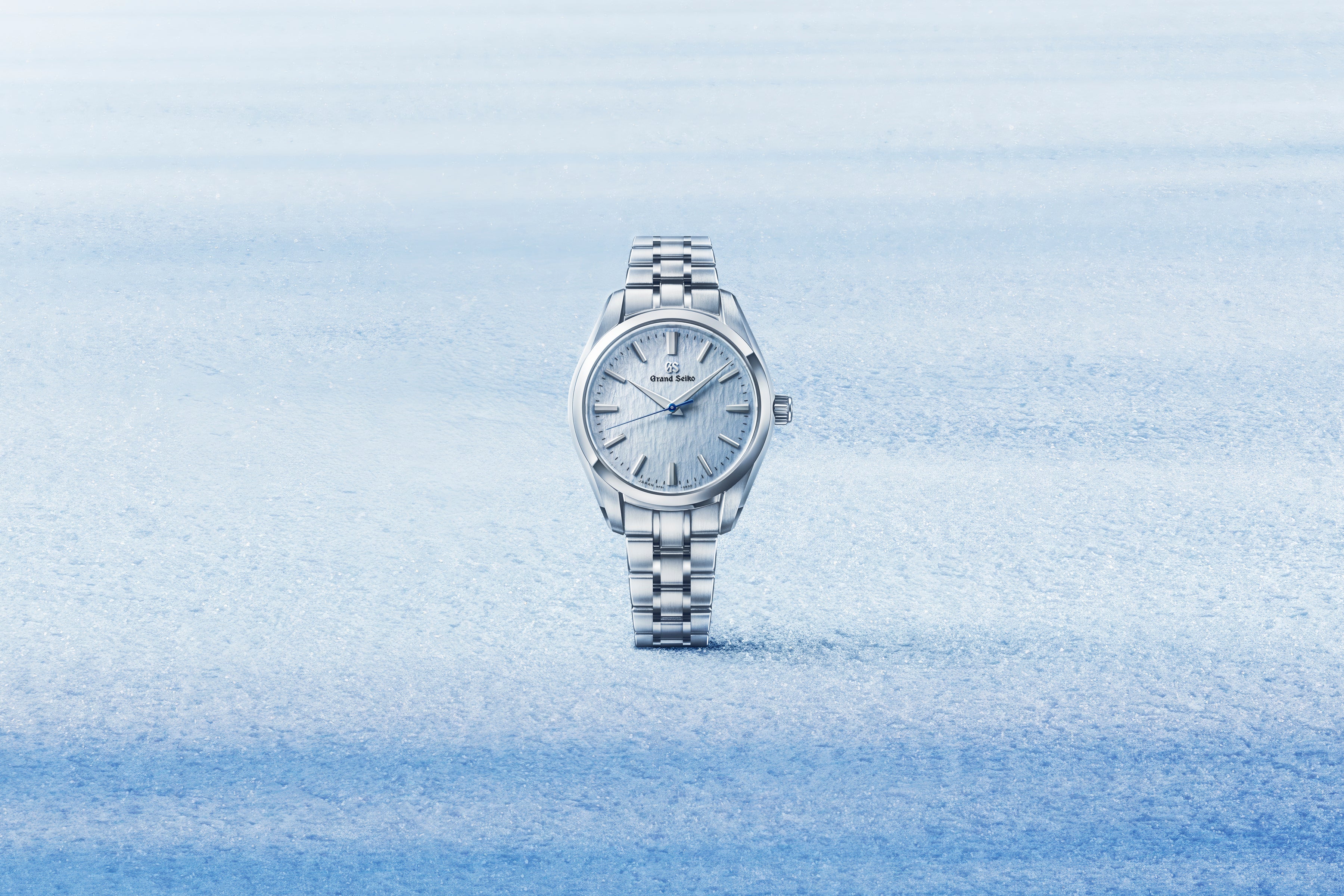 Silver grand seiko watch with blue dial on a light blue snowy gradient background