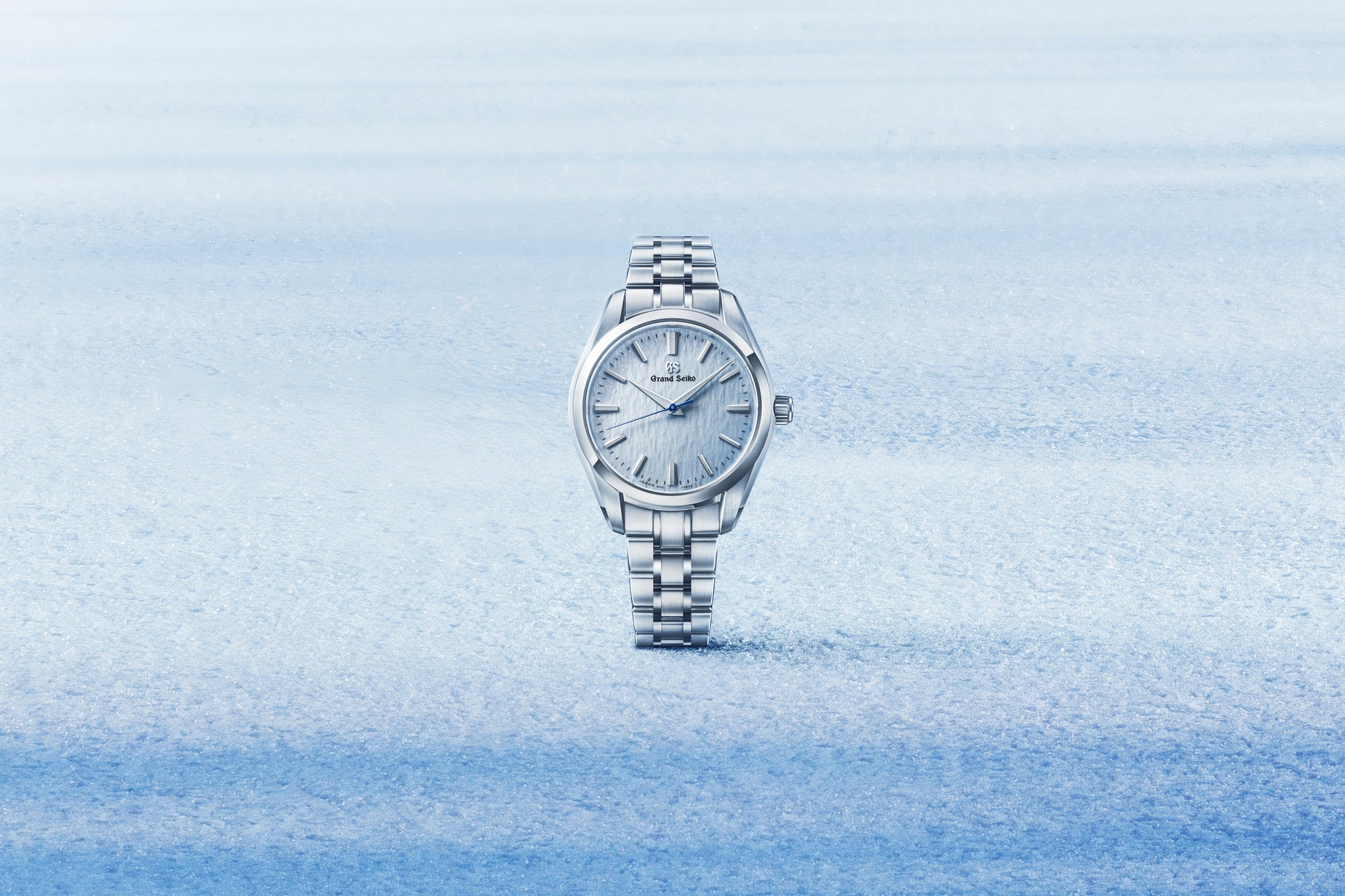Silver grand seiko watch with blue dial on a light blue snowy gradient background