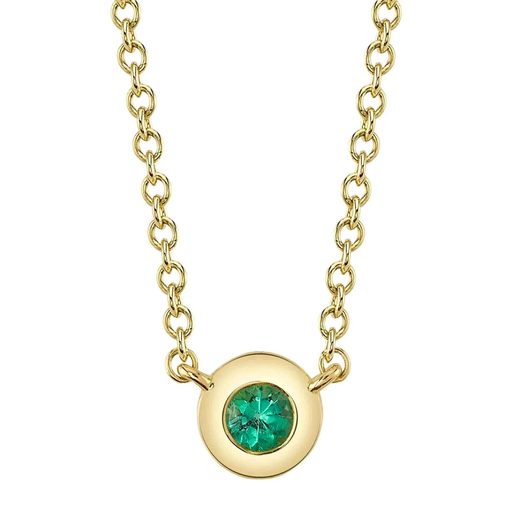 A front view of the Shy Creation Bailey Emerald Bezel Necklace (Style SC55026484) showcasing a dainty round natural green emerald in a smooth 14k yellow gold bezel pendant, suspended from a fine matching gold cable chain on a crisp white background.