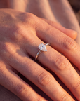 Close-up of a hand wearing a pear shaped lab diamond ring with a blurred background