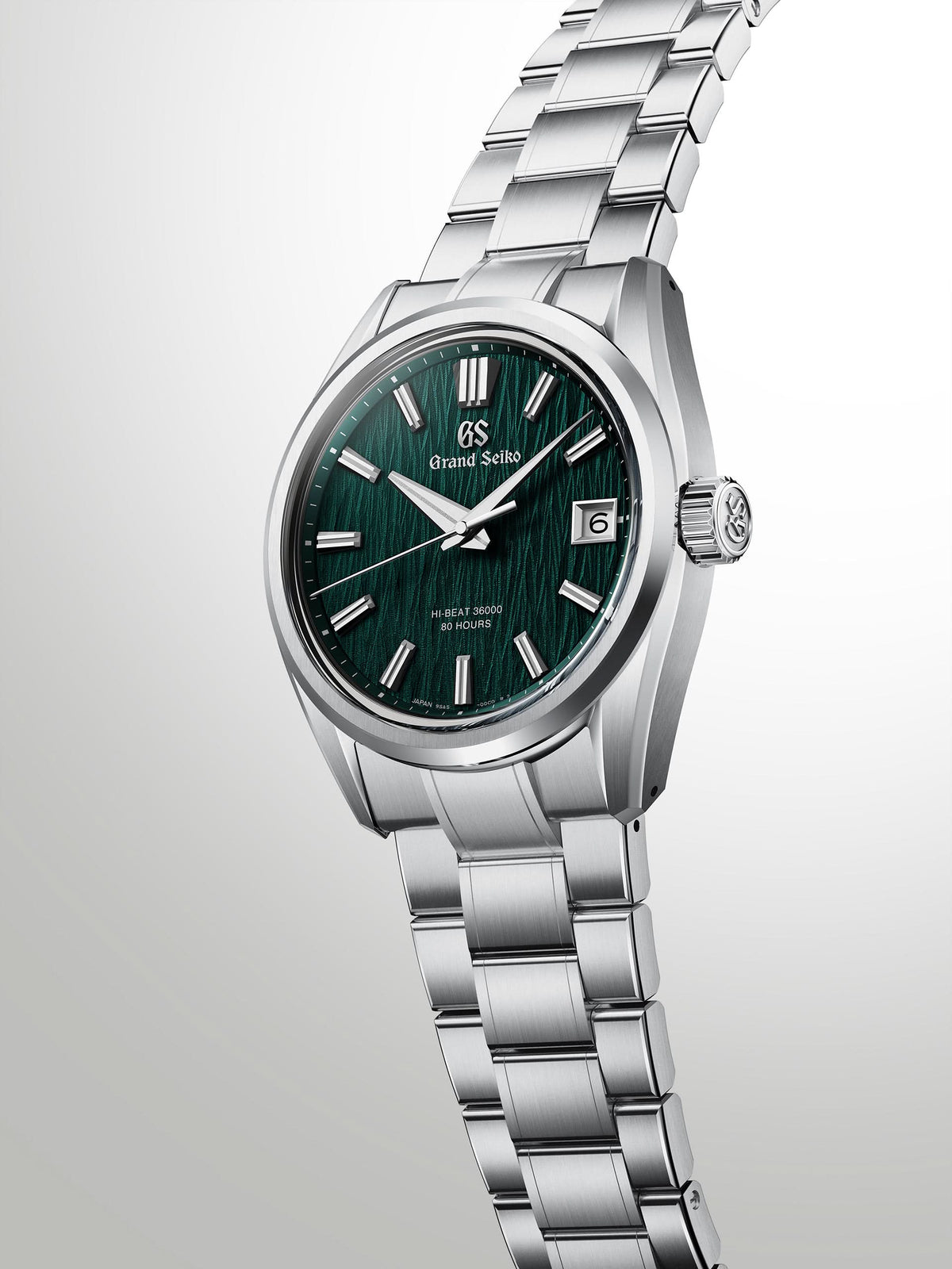 Silver watch with a green face on a light gray background