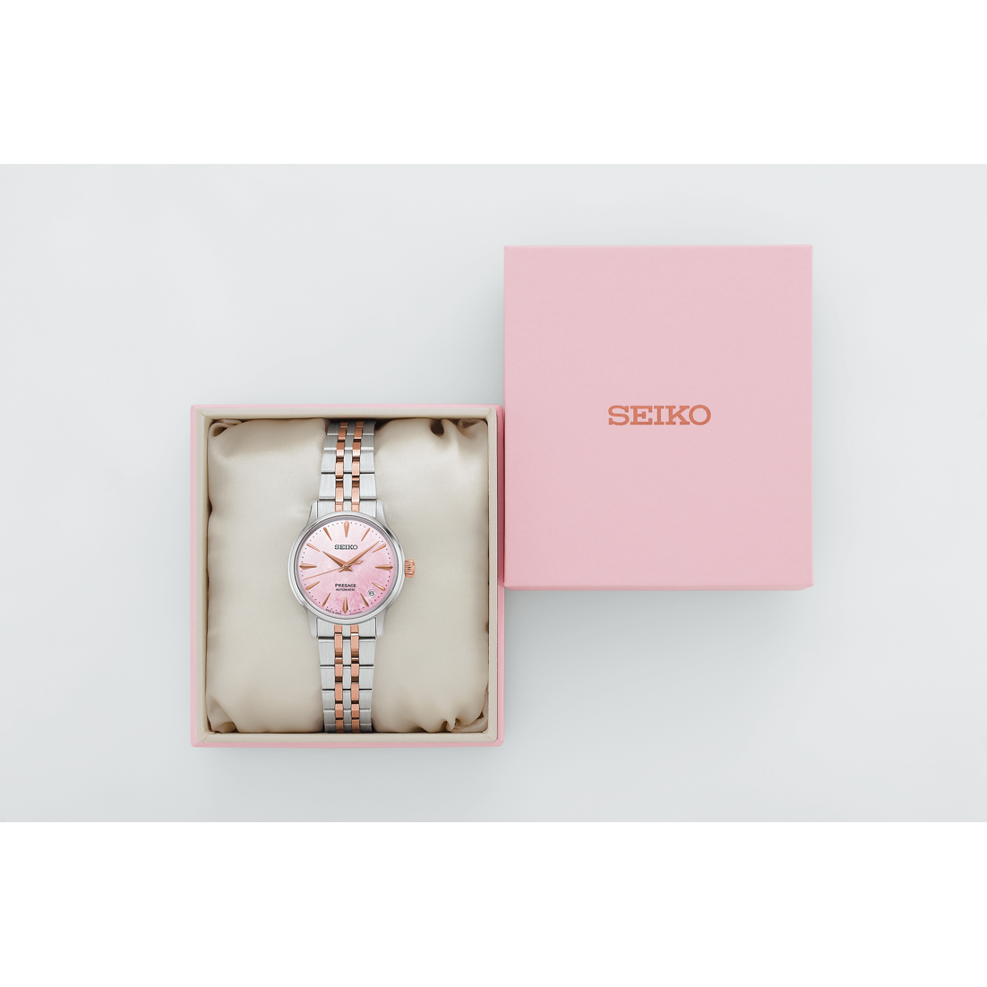 Seiko watch with pink face and silver bracelet in a pink box on a white background