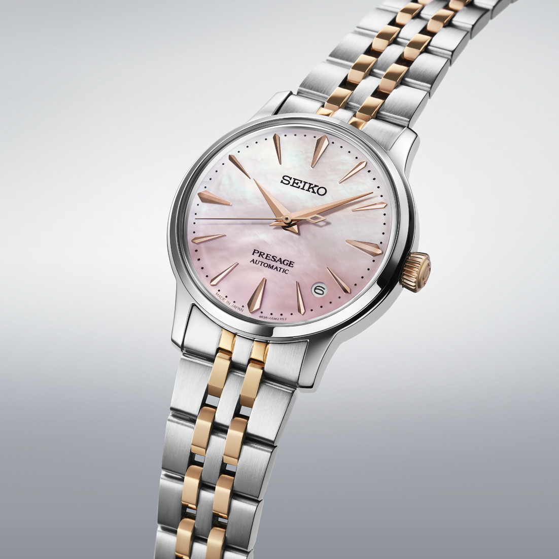 Seiko watch with pink dial and two-tone metal bracelet on a light gray background