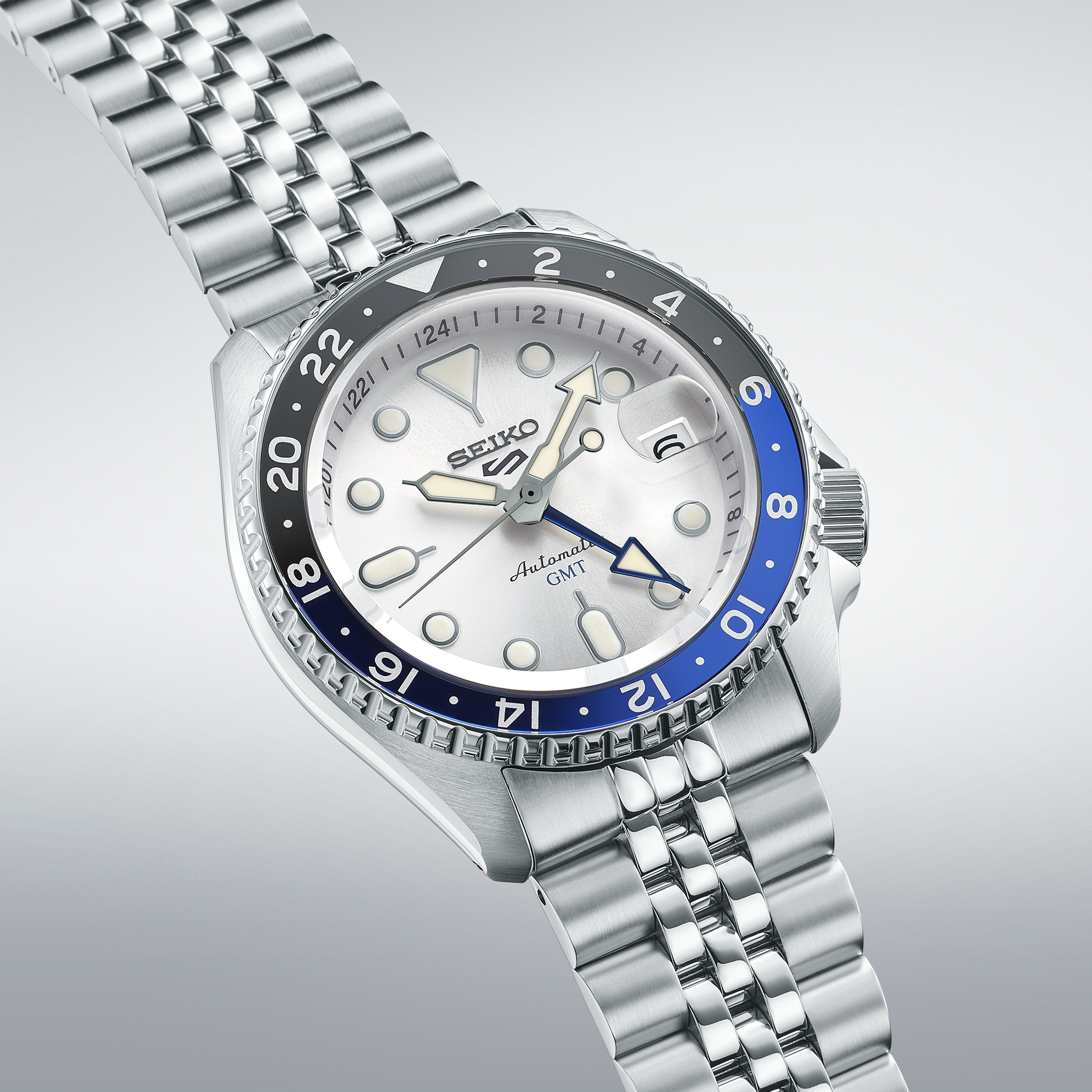 Silver Seiko watch with blue and black  bezel on a light gray background