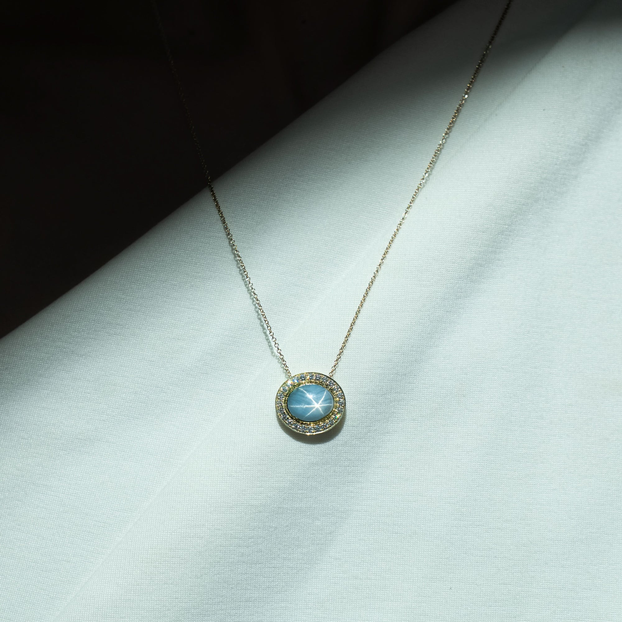 Necklace with a blue gemstone pendant on a light gray surface
