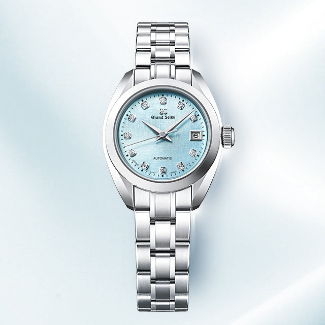 Silver watch with a light blue face on a soft blue background