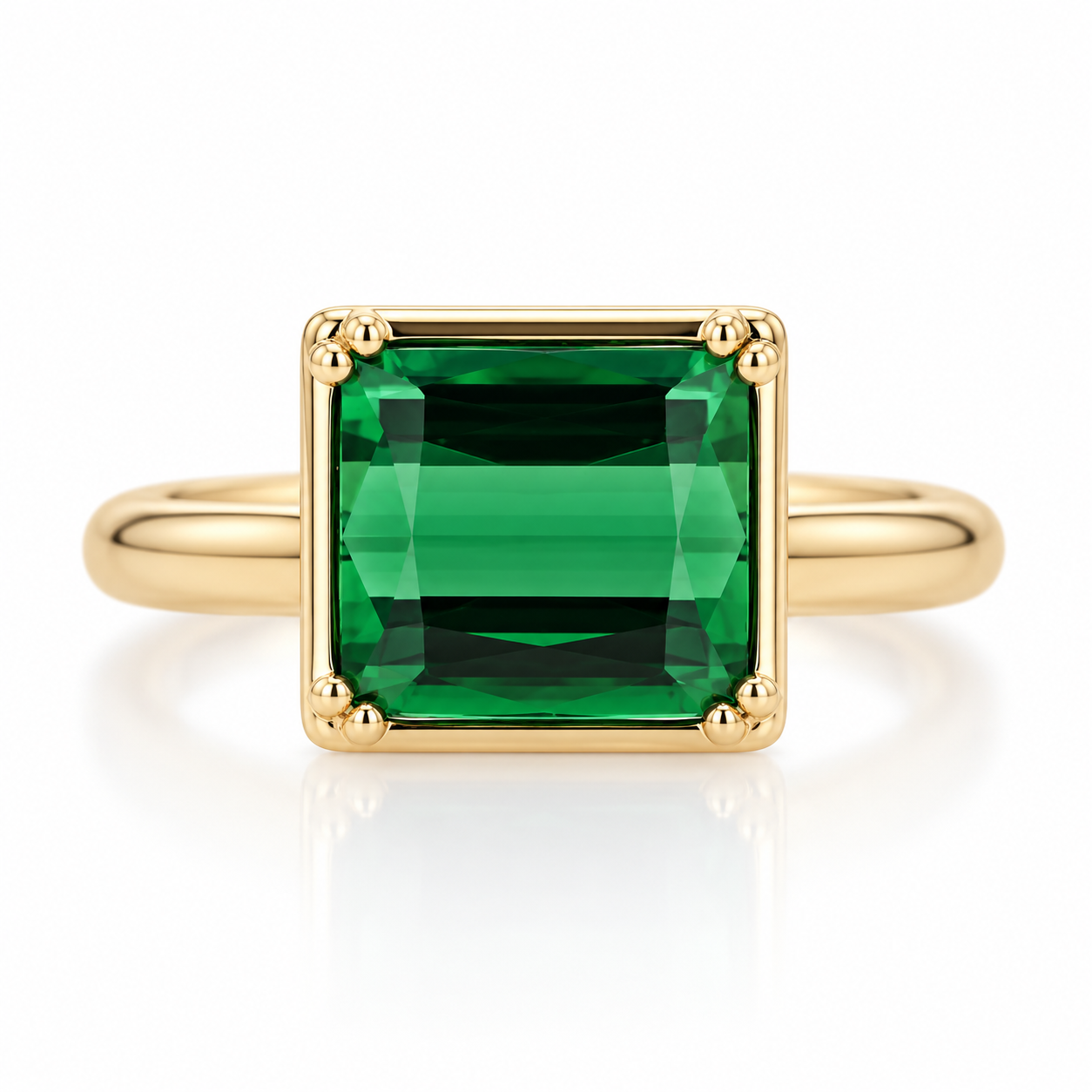 An green gemstone ring set in a polished yellow gold bezel with prongs with a matching gold band, shown on a clean white background with a soft reflection.
