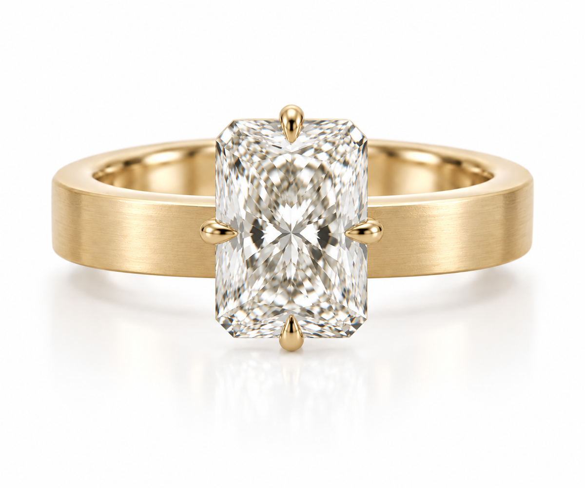 A yellow gold ring with a wide, brushed band and a large rectangular radiant-cut diamond center stone in a four-prong setting, shown on a clean white background.