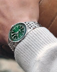 Breitling Green watch with silver strap on a wrist, blurred background