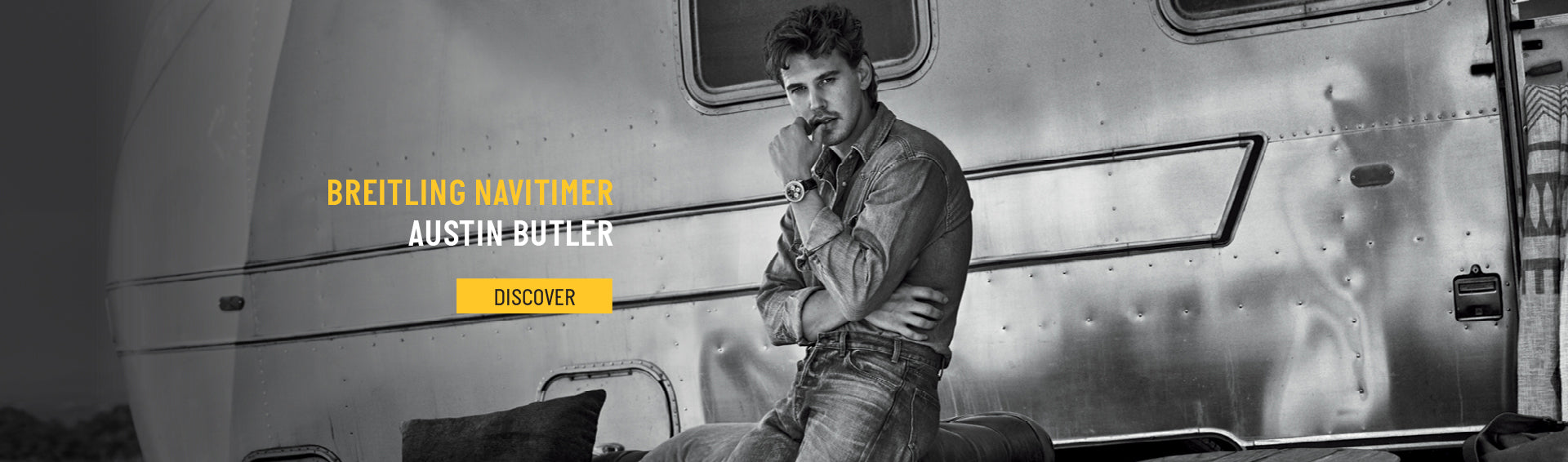 Austin butler posing with a navitimer watch in font of a trailer