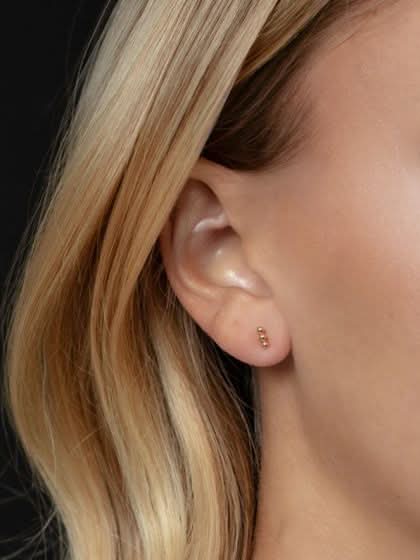 Close-up of a person wearing a gold earring with blonde hair.