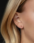 Close-up of a person wearing a gold earring with blonde hair.