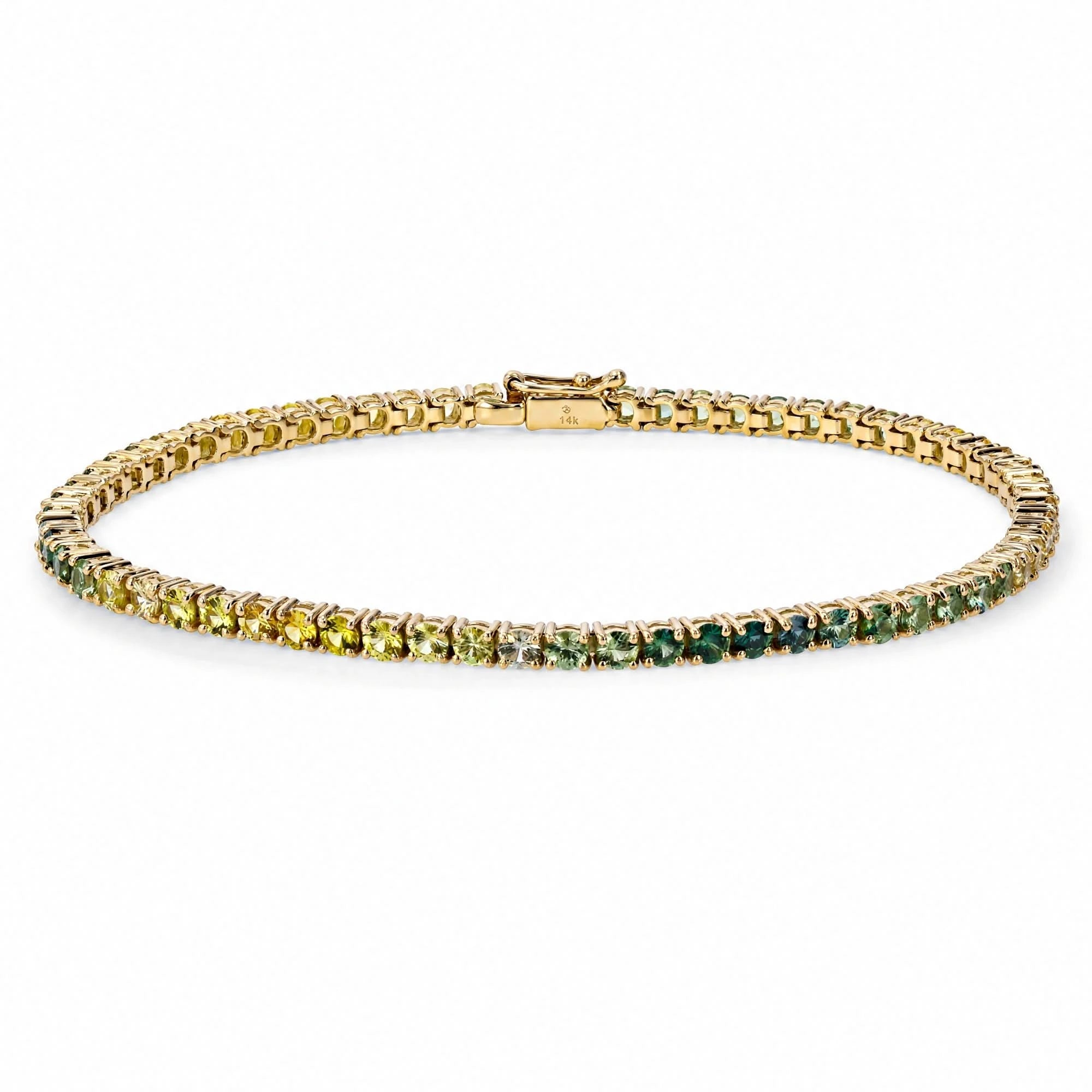 A gold tennis bracelet featuring a gradient of gemstones transitioning from yellow-green on one end to deep green on the other, displayed on a clean white background.