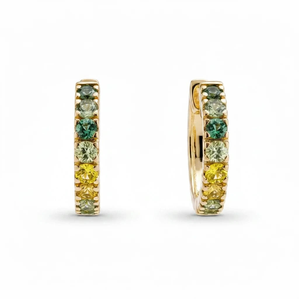 a pair of ombre green to yellow sapphire huggie hoop earrings in yellow gold on a white background