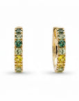 a pair of ombre green to yellow sapphire huggie hoop earrings in yellow gold on a white background
