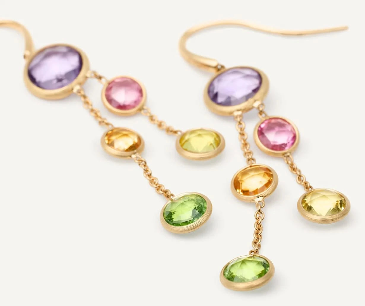 A pair of gold dangle earrings featuring oval-cut gemstones in purple, pink, yellow, and green, displayed on a clean white background.