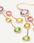 A pair of gold dangle earrings featuring oval-cut gemstones in purple, pink, yellow, and green, displayed on a clean white background.