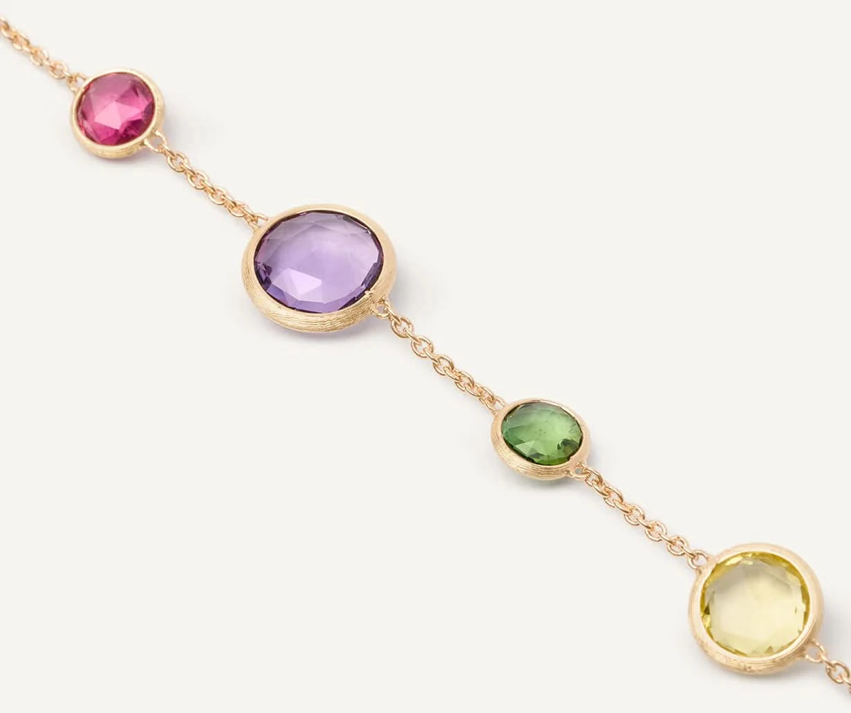 Close up of Gold bracelet with multicolored gemstones on a white background