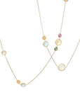 A delicate gold necklace featuring multiple small, round, colorful gemstone beads in pink, green, blue, and yellow, displayed against a solid off-white background.