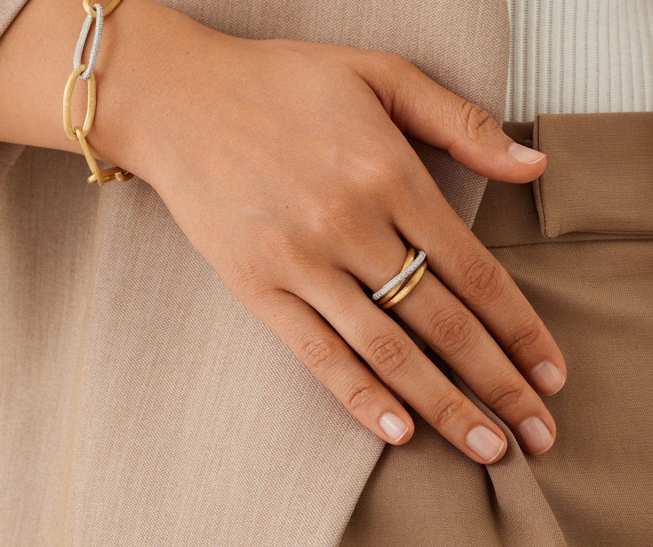 Hand wearing a gold ring on a beige fabric background