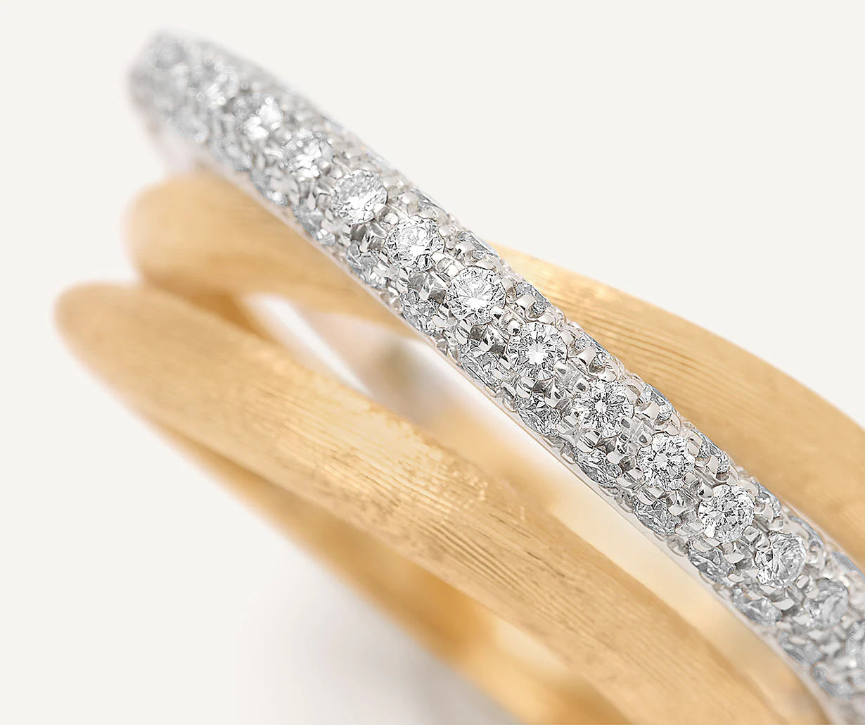 Gold and white gold ring with diamond accents on a light gray background close up