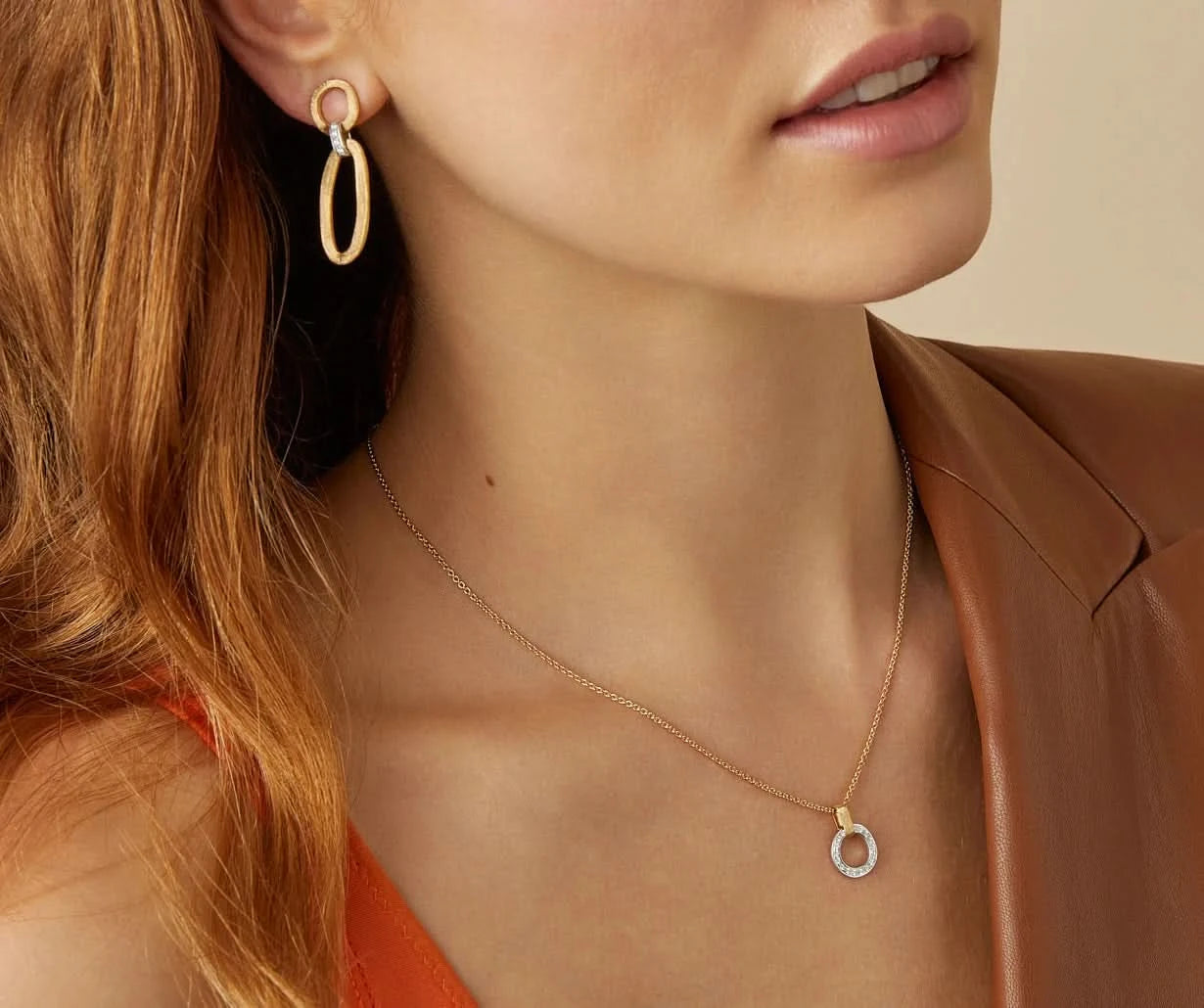 Close-up of a woman wearing gold hoop earrings and a gold necklace with a small pendant.