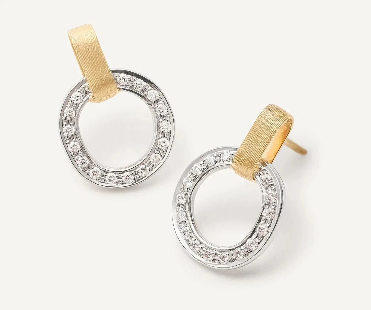 Pair of gold and silver hoop earrings on a light gray background