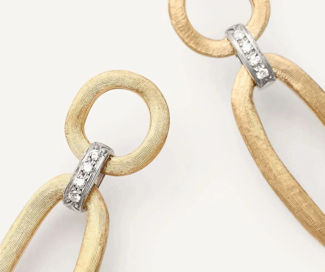 Goldstatement earrings with textured oval links and silver-toned diamond accents, shown on a clean white background.