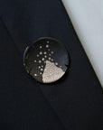 Logan James black steel and 18K white gold diamond brooch worn on black blazer lapel close-up