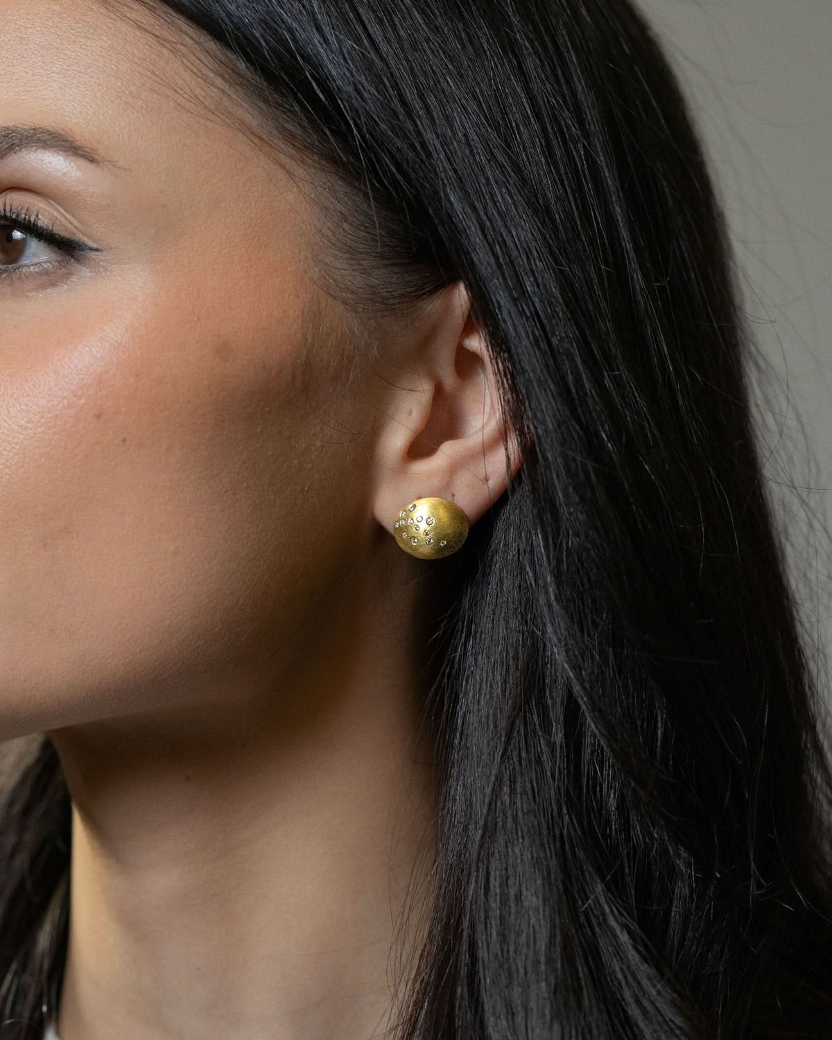 Model wearing Logan James Scatter 18K yellow gold oval diamond stud earring, lifestyle close-up