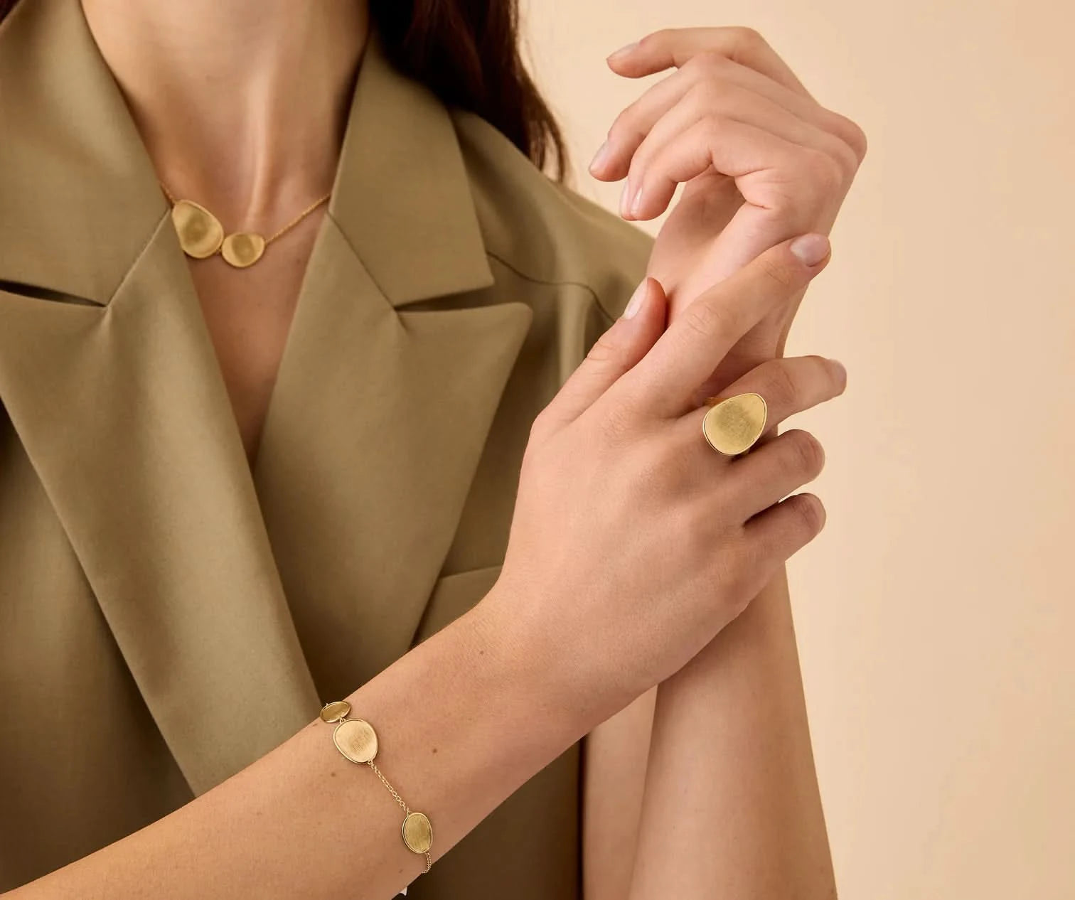 Person wearing gold jewelry on a beige background